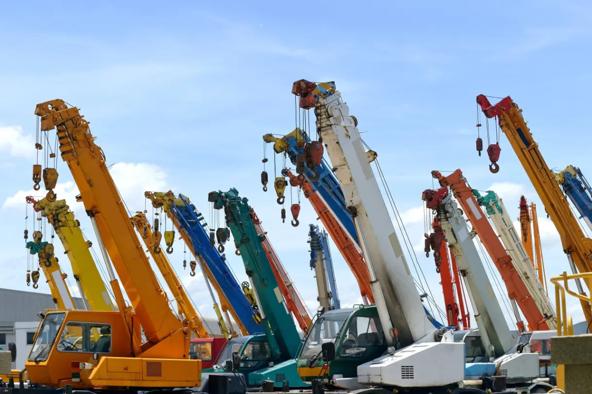A variety of colorful cranes parked in a lot, showcasing different types and sizes.