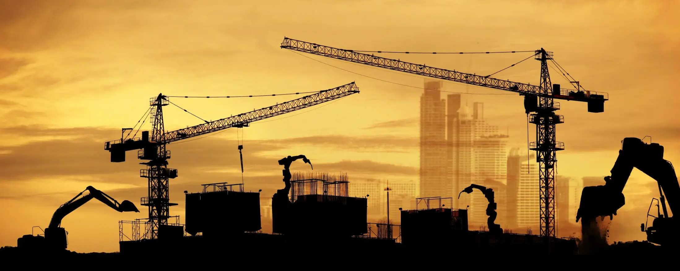 Silhouette of construction cranes against a skyline, highlighting an active construction site at sunset.