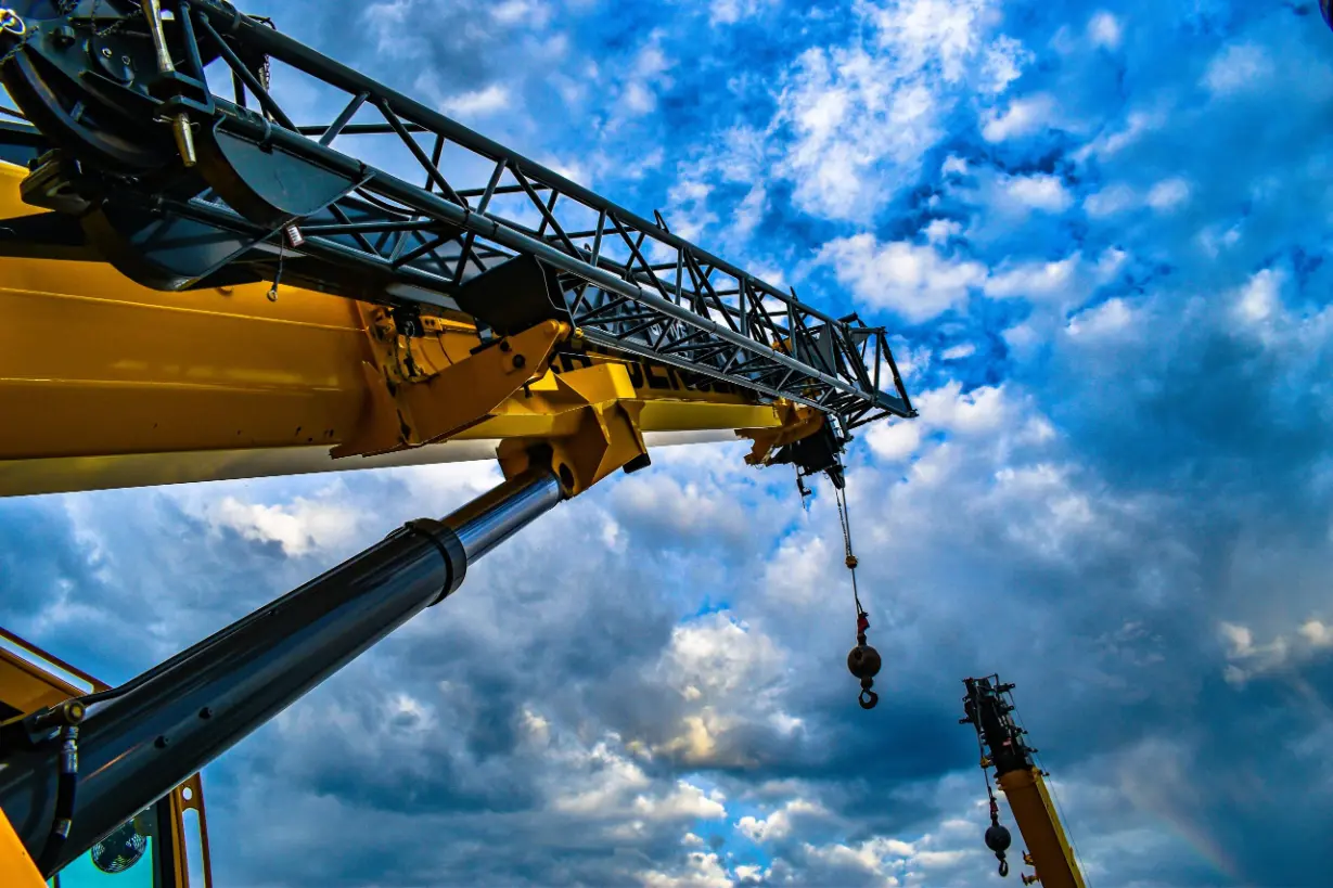 A crane lifting a large object against a clear blue sky, showcasing its strength and construction capabilities.
