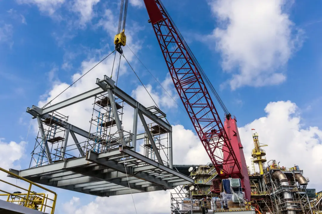 A construction crane elevating a heavy structure, showcasing its lifting capabilities.